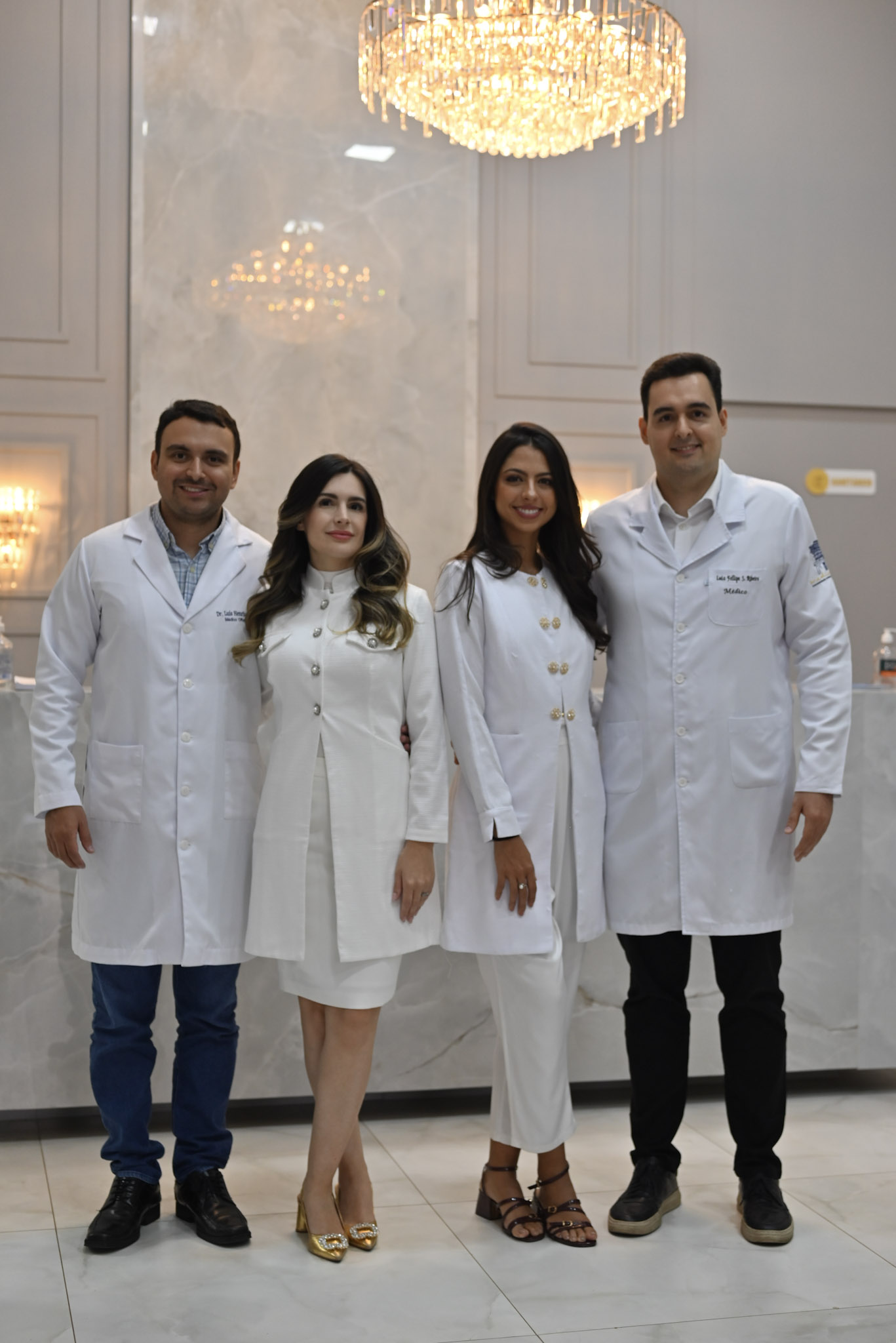 Equipe médica da Clínica Eye Center reunida em recepção sofisticada, jalecos brancos, ambiente elegante com mármore claro e lustre de cristal iluminado, fotografia realista institucional