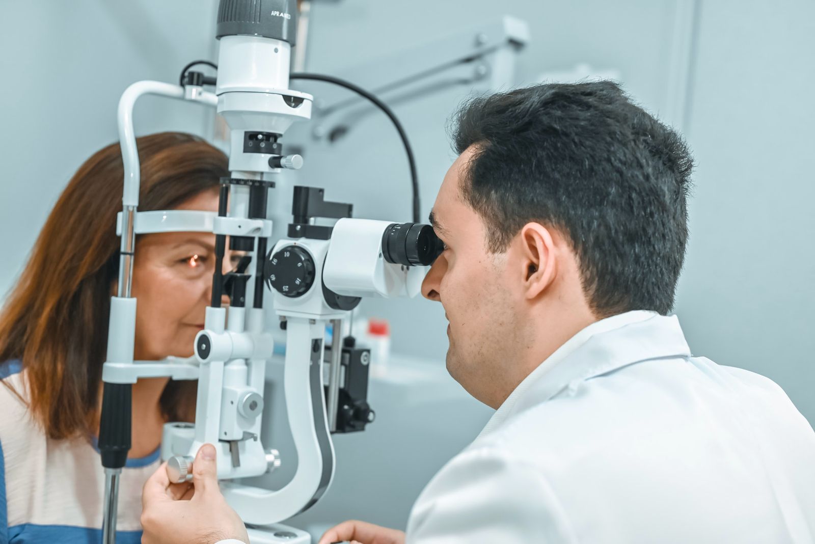 Médico oftalmologista realizando exame de lâmpada de fenda em paciente, close-up do procedimento clínico, ambiente consultório com iluminação neutra, fotografia realista